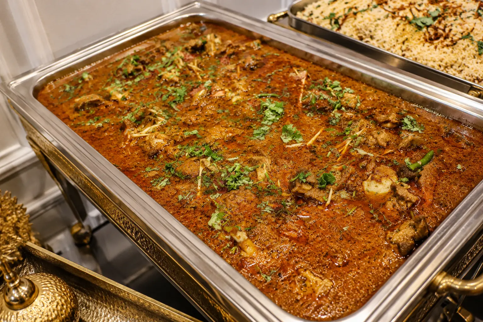 Bulk goat curry tray served with rice at a party