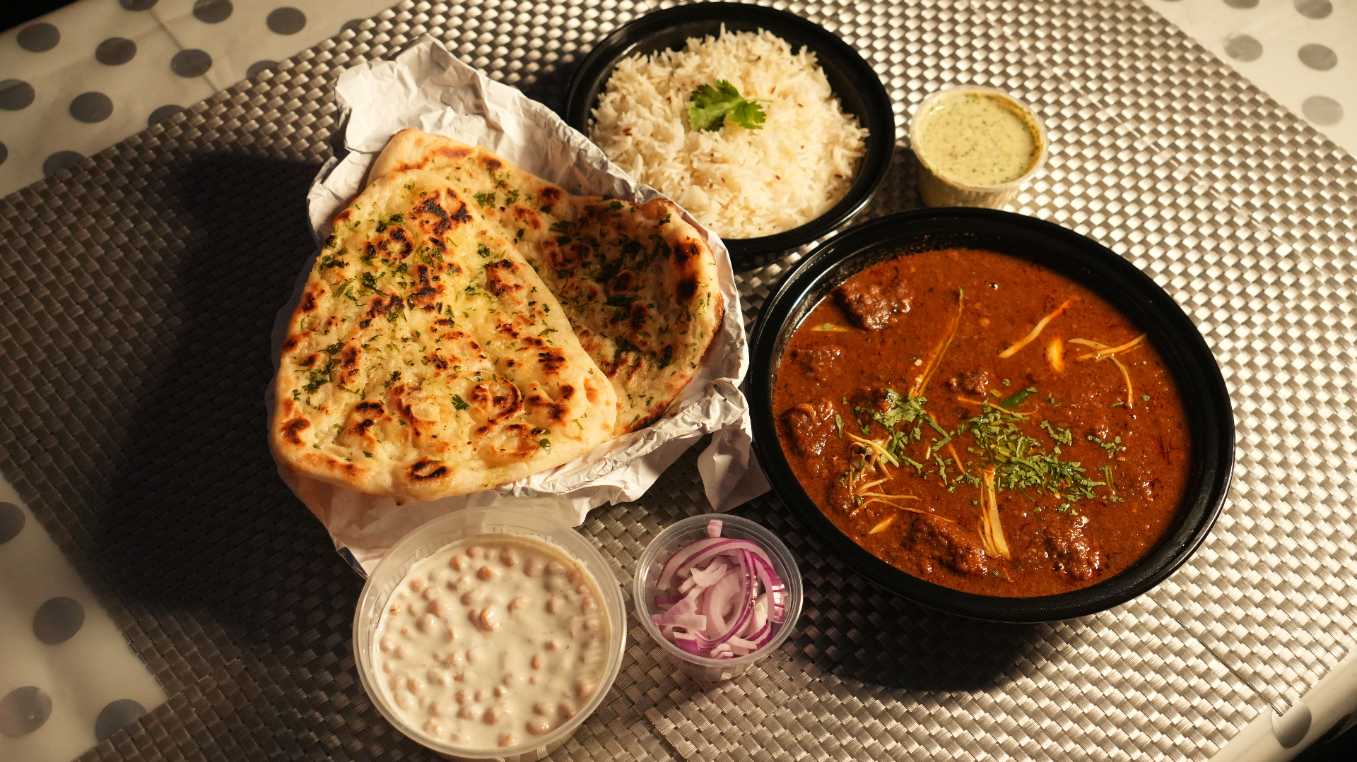 Goat curry with garlic naan, jeera rice, raita, onions, and mint chutney